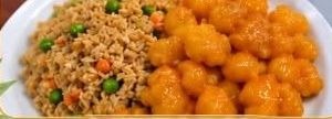 Orange chicken with fried rice and peas on a white plate